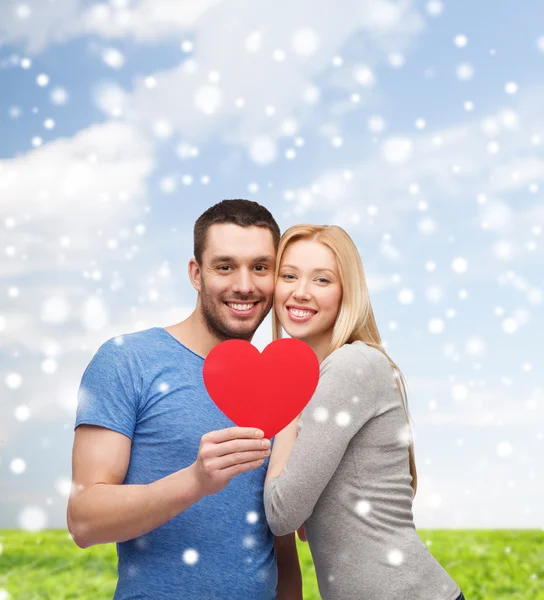 Happy couple with red heart shape hugging outdoors — Stock Photo, Image