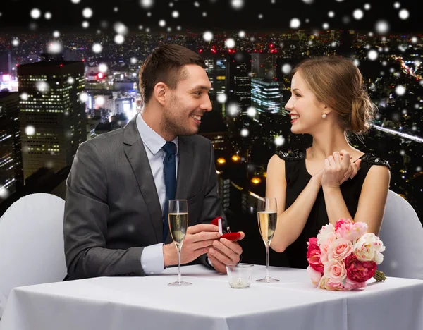 Smiling couple with red gift box at restaurant — Stock Photo, Image