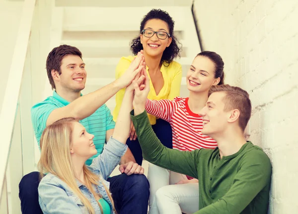 Sonriendo estudiantes haciendo alta cinco gesto sentado — Foto de Stock