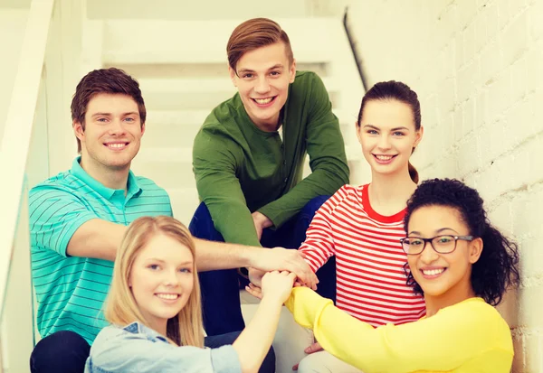 Studenti sorridenti con le mani uno sopra l'altro — Foto Stock