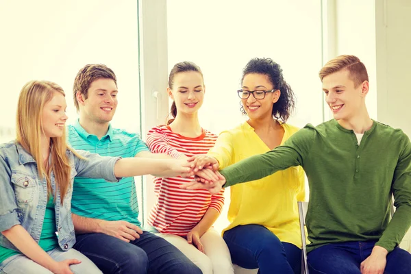 Smiling students with hands on top of each other — Stock Photo, Image