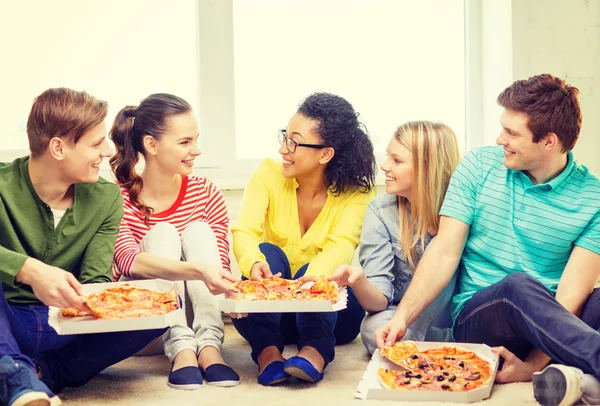 Pět usmívající se teenageři jíst pizzu doma — Stock fotografie