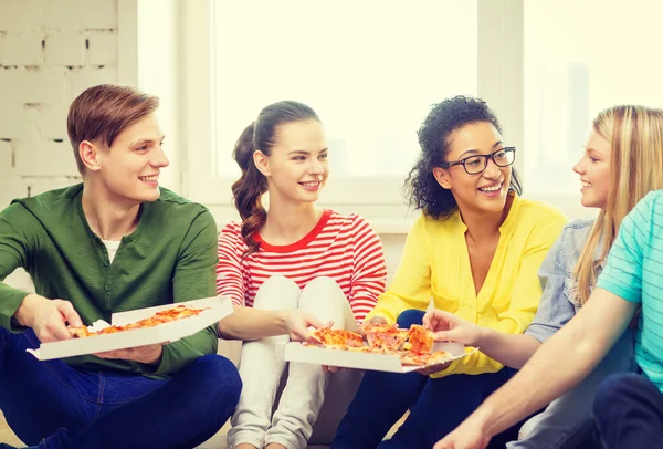 Fünf lächelnde Teenager, die zu Hause Pizza essen — Stockfoto