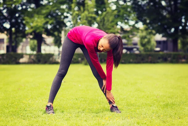 Sonriente negro mujer estirando la pierna al aire libre —  Fotos de Stock