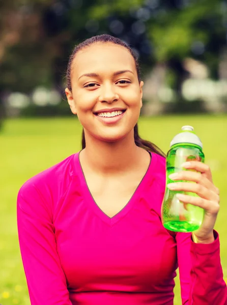 Smiling teenage girl showing bottle — Stock Photo, Image