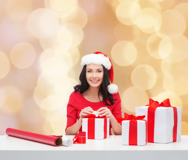 Lachende vrouw in helper KERSTMUTS verpakking geschenken — Stockfoto