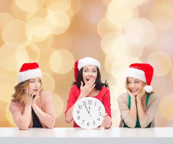 Smiling women in santa helper hats with clock — Stock Photo, Image