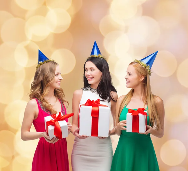 Smiling women in party caps with gift boxes — Stock Photo, Image