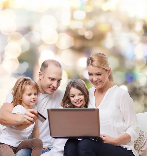 Familia feliz con ordenador portátil y tarjeta de crédito — Foto de Stock