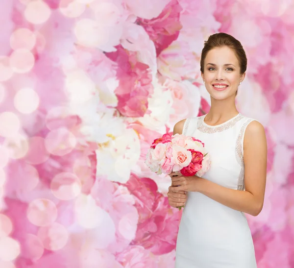 Uśmiechnięta kobieta w białej sukni z bukietem róż — Zdjęcie stockowe