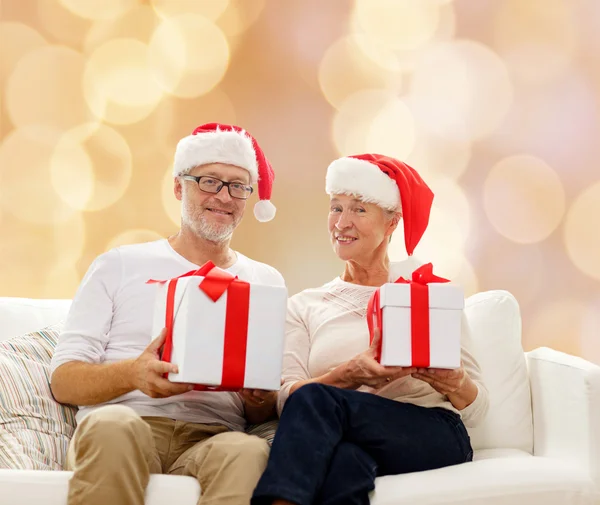 Glad äldre par i santa hattar med presentförpackning — Stockfoto