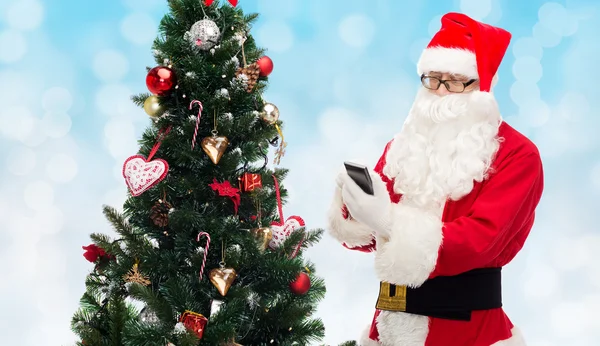 Santa claus com smartphone e árvore de natal — Fotografia de Stock