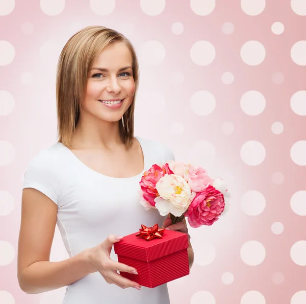 Lachende jonge vrouw met doos van de gift en bloemen — Stockfoto