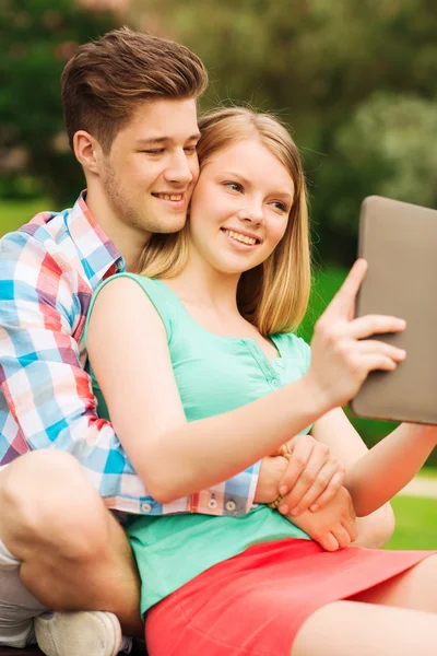 Smiling couple with tablet pc making selfie — Stock Photo, Image