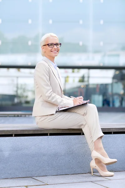 Jeune femme d'affaires souriante avec bloc-notes à l'extérieur — Photo