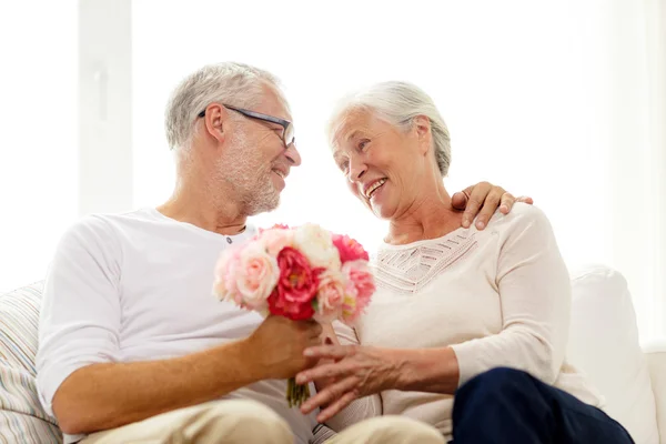 Happy senior couple with bunch of flowers at home — Stock Photo, Image
