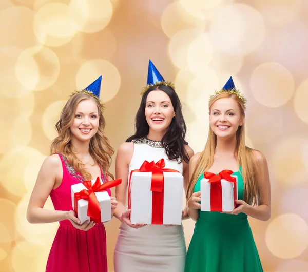 Mujeres sonrientes en gorras de fiesta con cajas de regalo — Foto de Stock