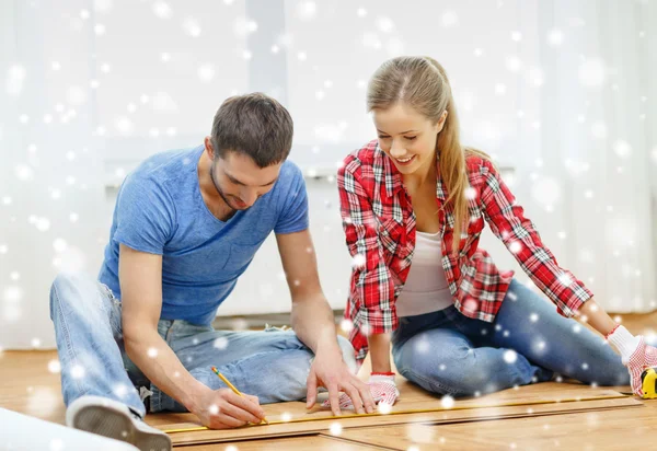 Smiling couple measuring wood flooring — Stock Photo, Image