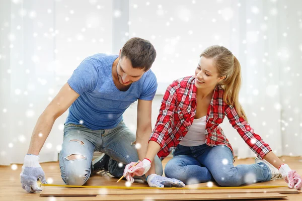 Smiling couple measuring wood flooring — Stock Photo, Image