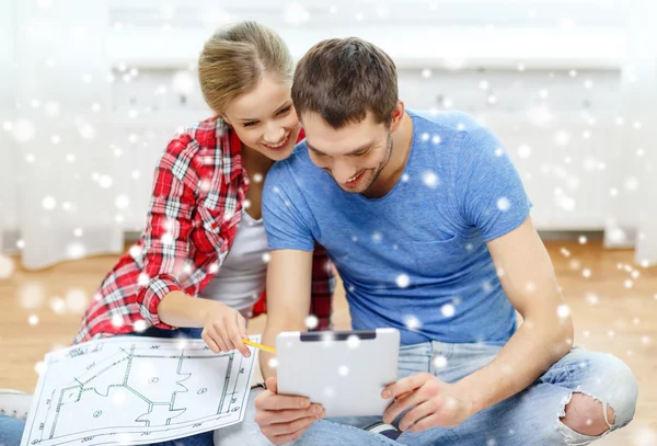 Smiling couple with tablet and blueprint at home — Stock Photo, Image