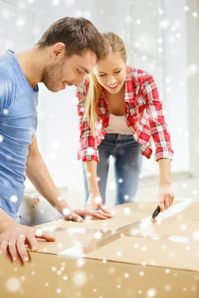 Smiling couple opening big cardboard box — Stock Photo, Image