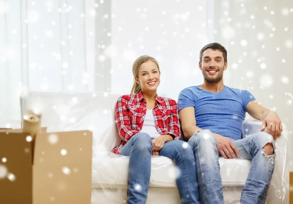 Pareja sonriente relajándose en un sofá en un nuevo hogar — Foto de Stock