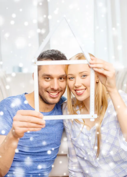 Smiling couple holding house model at home — Stock Photo, Image