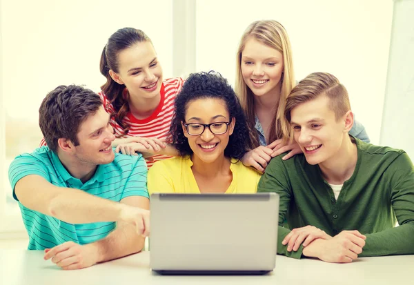 Smiling students looking at laptop at school — Stock Photo, Image