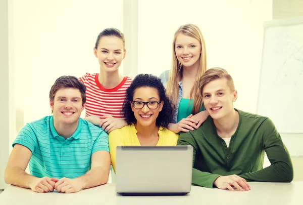 Lachende studenten met laptop op school — Stockfoto