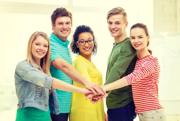 Smiling students with hands on top of each other — Stock Photo, Image