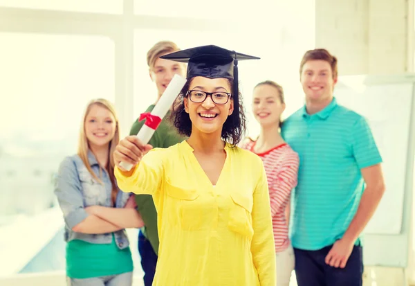 Lachende vrouwelijke student met diploma en hoek-cap — Stockfoto