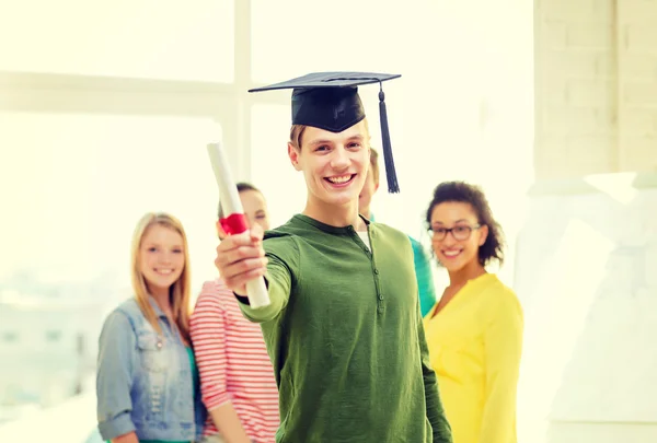 Sorridente estudante do sexo masculino com diploma e boné de canto — Fotografia de Stock