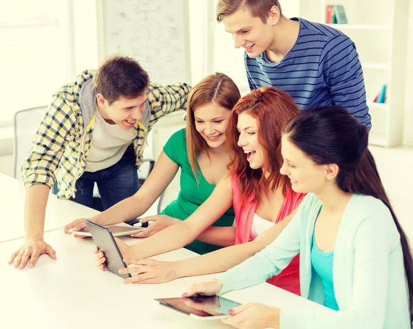 Lachende studenten met de tablet pc op school — Stockfoto