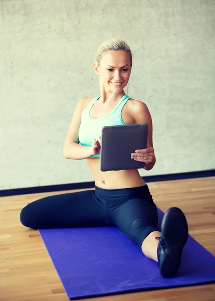 Lachende vrouw met tablet pc in de sportschool — Stockfoto