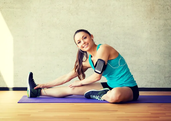 Leende kvinna sträcker benet på matta i gym — Stockfoto