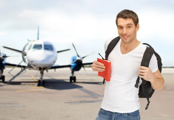 Smiling student with backpack and book at airport — Stock Photo, Image