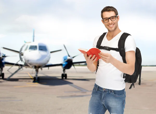 Smiling student with backpack and book at airport — Stock Photo, Image