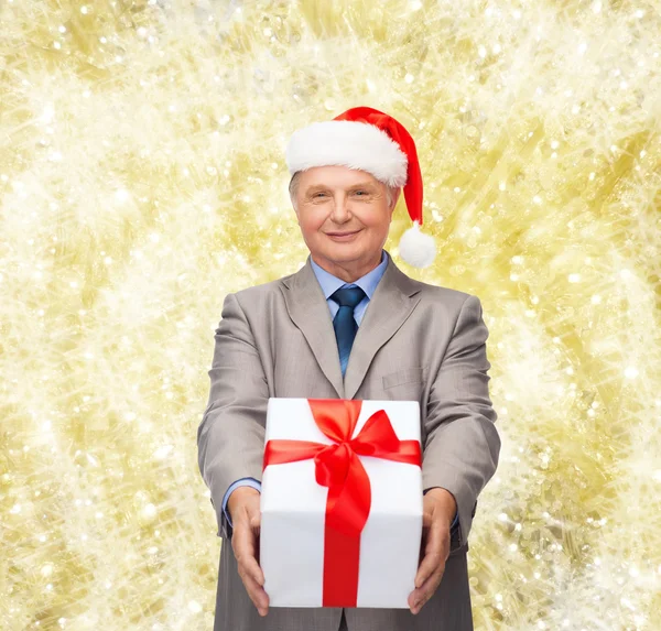 Sorrindo homem de terno e chapéu de Papai Noel ajudante com presente — Fotografia de Stock