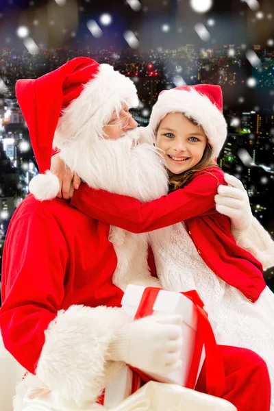 Smiling little girl with santa claus and gifts — Stock Photo, Image