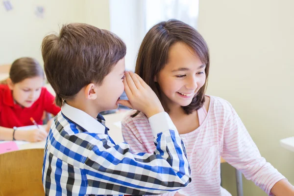 Smiling schoolboy whispering to classmate ear — Stock Photo, Image