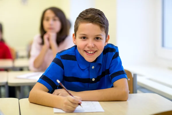 Grupp av skolbarnen skriva prov i klassrummet — Stockfoto