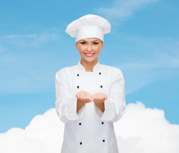 Sorridente chef femminile che tiene qualcosa sulle mani — Foto Stock