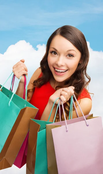 Mulher sorridente com sacos de compras coloridos — Fotografia de Stock