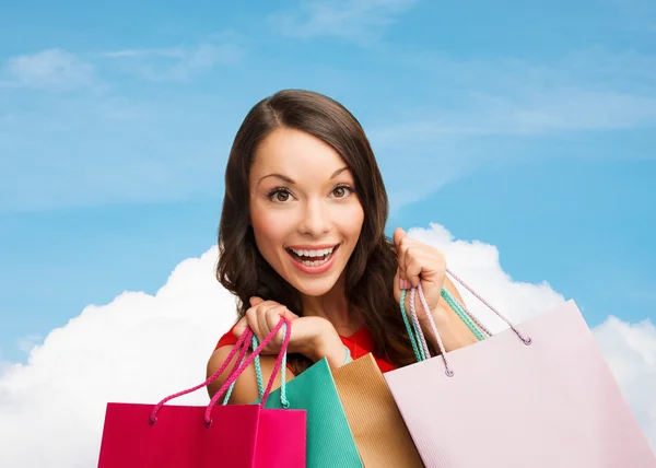 Mulher sorridente com sacos de compras coloridos — Fotografia de Stock