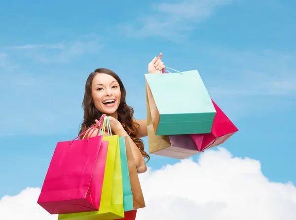 Mulher sorridente com sacos de compras coloridos — Fotografia de Stock