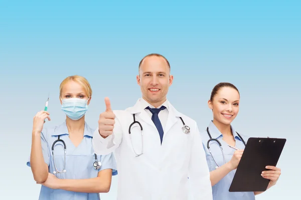 Группа улыбающихся врачей с поднятыми пальцами — стоковое фото