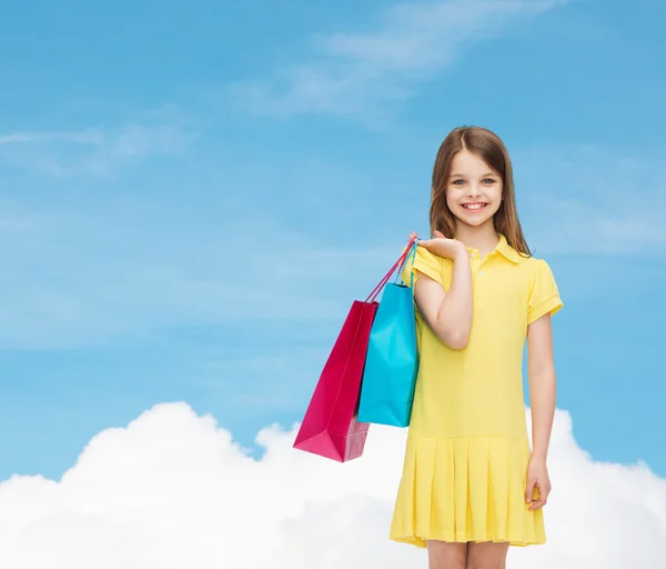 Lachende meisje in jurk met shopping tassen — Stockfoto