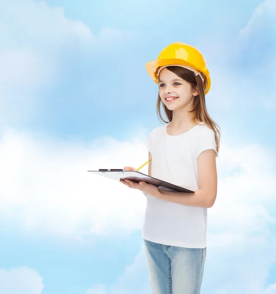 Petite fille souriante en hardhat avec presse-papiers — Photo