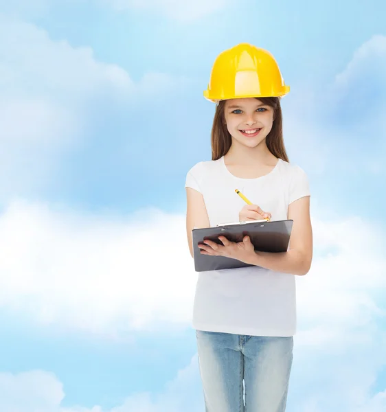 Niña sonriente en hardhat con portapapeles — Foto de Stock