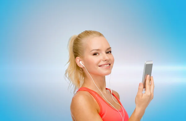 Sorrindo mulher desportiva com smartphone e fones de ouvido — Fotografia de Stock